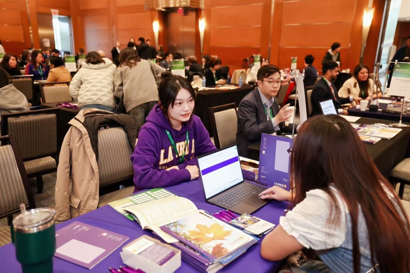 Serena in a Laurier hoodie talking with a prospective student at a recruitment fair